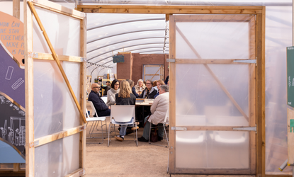 An open door looking into a space at Civic Square that has groups of people sat around tables having a discussion
