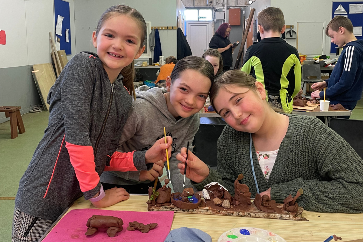 Cheshire Young Carers-Three young people smile as they paint their clay models