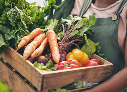 Close up of someone holding a wooden box full of vegetables
