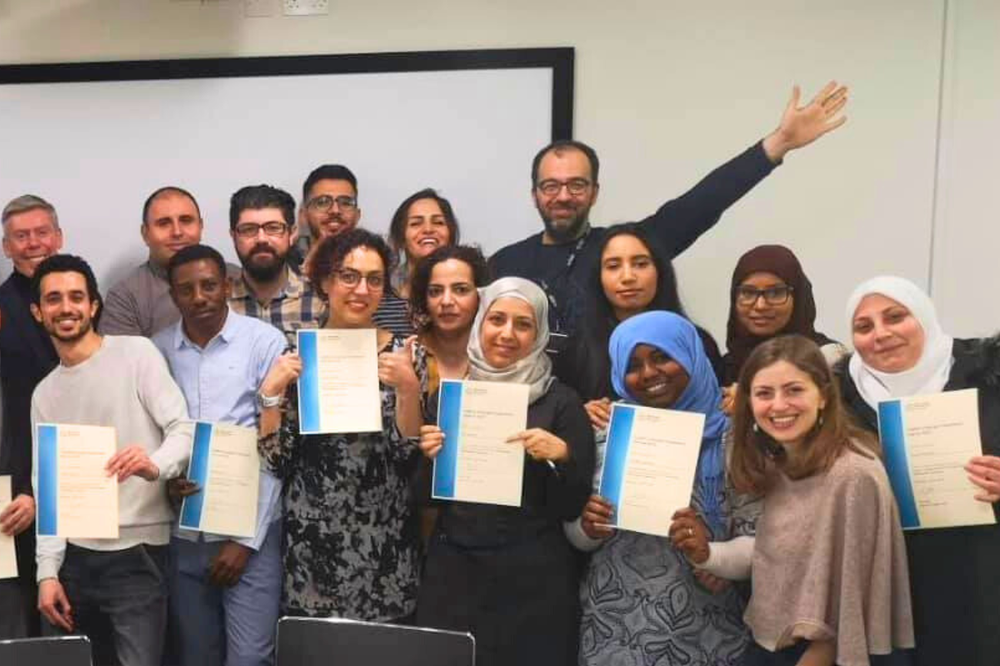 RefuAid-Large group of people standing in a room posing for a picture
