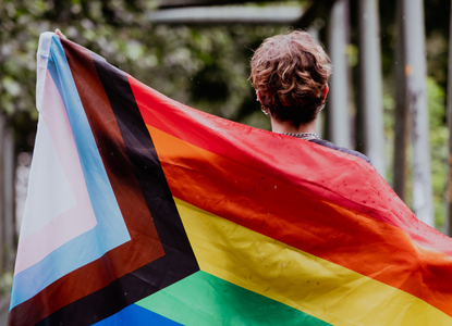 Stock photo-person holding a large progress pride flag.png